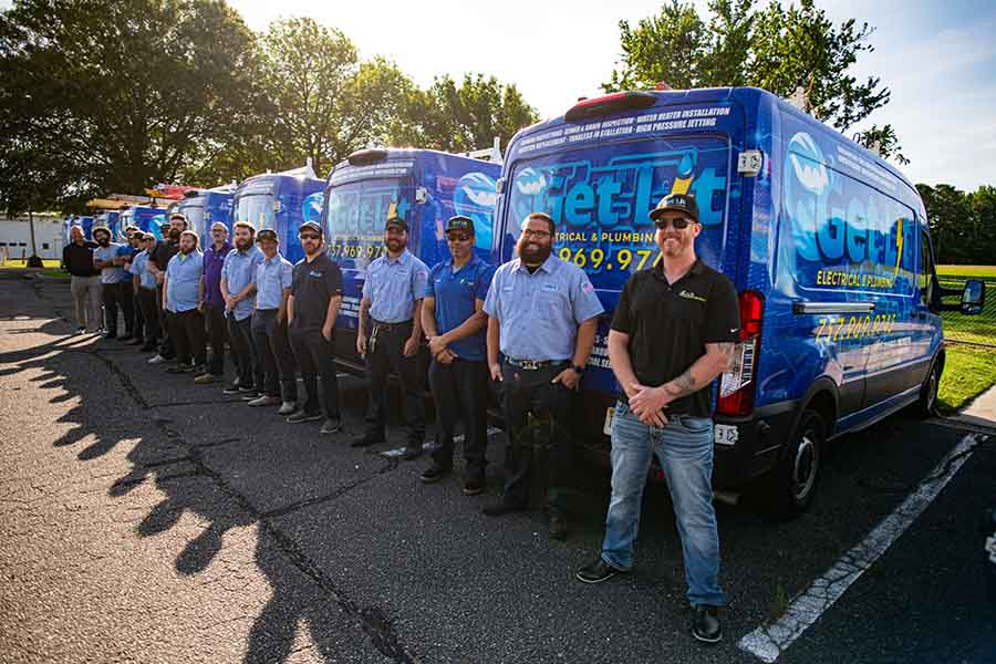 A group of workers in uniform stands in a line beside several blue service vans in a parking lot on a sunny day, showcasing the team spirit at a company that's hiring for new careers.